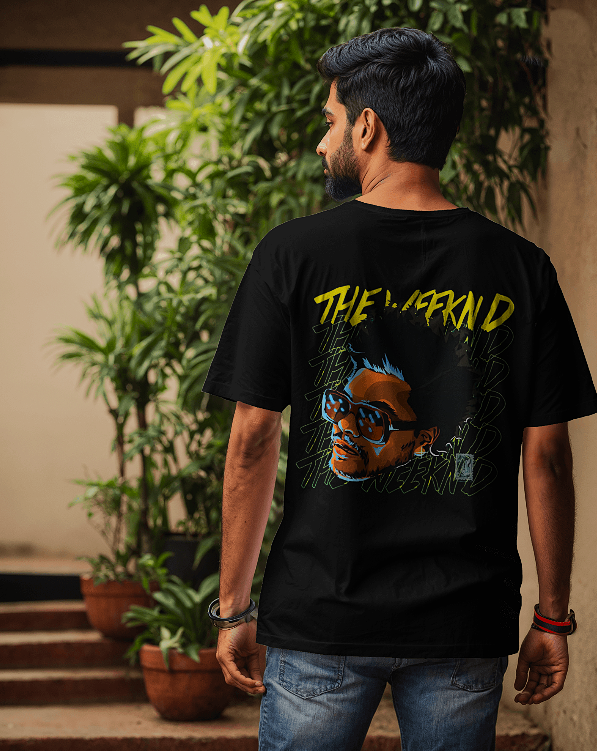 Person wearing a black t-shirt with a graphic design and text, standing outdoors.